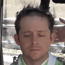 a man with his eyes closed is being shaved by a machine