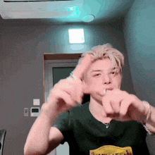 a man wearing a green shirt is making a heart shape with his hands