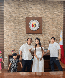 a group of people standing in front of a wall with the seal of the republic of the philippines on it