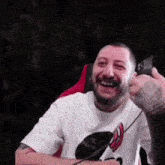 a man with a tattoo on his arm is laughing while holding a controller .