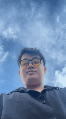 a man wearing glasses is looking up at the sky