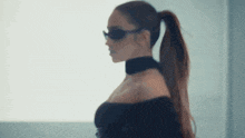 the woman is wearing sunglasses and a choker and has a ponytail .