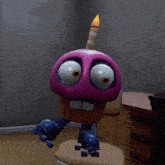 a purple cupcake with a candle on top of it sits on a chair