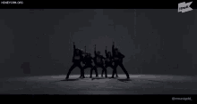 a group of people are standing in a row with their arms in the air