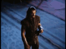 a man with long hair and a sword is standing on a staircase holding a sword .