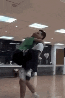 a man is carrying another man on his back in a dance studio .