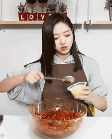 a woman in an apron is mixing a bowl of food with a spoon