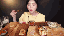a woman is sitting at a table eating a meal with chopsticks