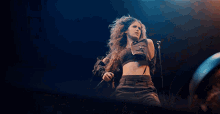 a woman is singing into a microphone with her hair blowing in the wind