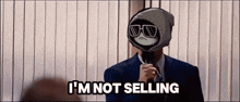 a man in a suit says i 'm not selling in front of a window