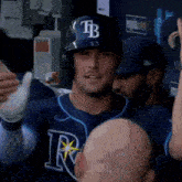 a baseball player wearing a tb hat is standing in the dugout .