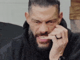 a man with a beard and a ring on his finger is biting his finger .