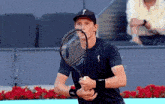 a man is holding a tennis racquet with the letter s on his hat