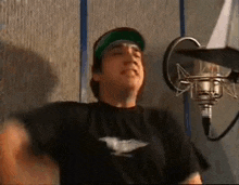 a man is standing in front of a microphone in a recording studio .