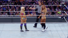two women are standing in a wrestling ring with a referee