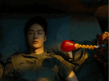 a man laying in bed with a red boxing glove on his shoulder