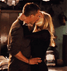 a man and a woman are kissing in a room with a jar in the background