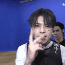 a man making a peace sign in front of a blue wall