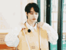 a young man is wearing a yellow vest and a white shirt .