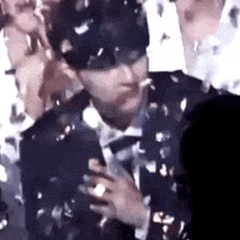 a man in a suit and bow tie is standing in a crowd .
