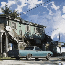a blue ford truck is parked in front of a green house