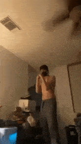 a shirtless man wearing a mask is standing in a room .