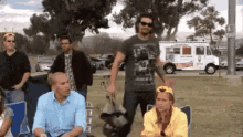 a group of people are gathered in a park with a white truck in the background .