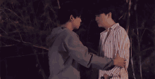a couple of men hugging each other in a dark forest