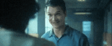 a man in a blue shirt is talking to another man .