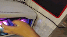 a person 's hand is reaching into a white box with purple lights coming out of it