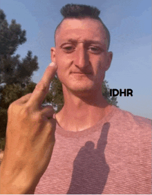 a man giving the middle finger with idhr written on the bottom right