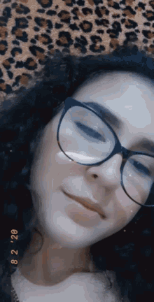 a girl wearing glasses is laying on a leopard print blanket .