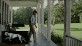 a man walking on a porch next to a painting of a horse