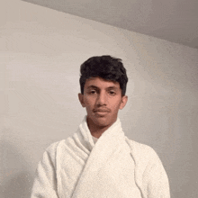a young man is wearing a white robe and looking at the camera