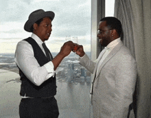 two men toasting with champagne glasses in front of a large window