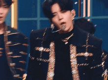 a man wearing a black jacket with rhinestones on it is singing into a microphone