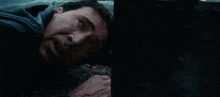 a man is laying on the ground in a dark room with his head on a wall .