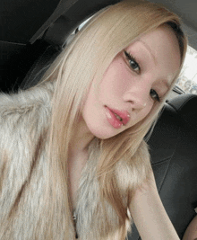 a woman in a fur vest is taking a selfie in a car