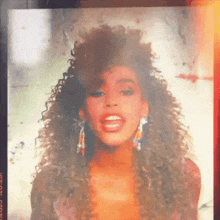 a close up of a woman with curly hair and earrings with a blurred background
