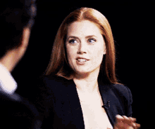 a woman in a black jacket talking to a man