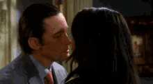 a man in a suit and tie kisses a woman with long dark hair