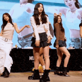 a group of girls are dancing in front of a sign that says mu on it