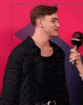 a man in a black striped shirt is being interviewed by someone holding a microphone with a lightning bolt on it