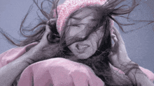 a woman wearing a pink hat and a pink jacket holds her hair