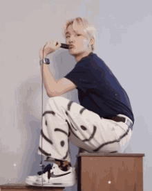 a young man is sitting on a stool holding a microphone