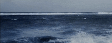 a large body of water with waves crashing against a rocky shore .