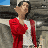 a man in a red cardigan and white shirt is blowing a kiss