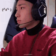 a man wearing headphones and a microphone is sitting in front of a computer .