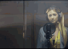 a woman wearing headphones and a yellow shirt is singing into a microphone