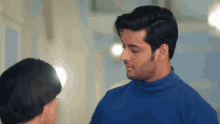 a man in a blue turtleneck sweater is looking at a woman